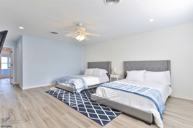 bedroom with light hardwood / wood-style flooring, ceiling fan, and a textured ceiling