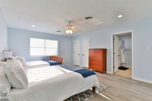 bedroom with ceiling fan, a textured ceiling, light hardwood / wood-style flooring, and ensuite bathroom