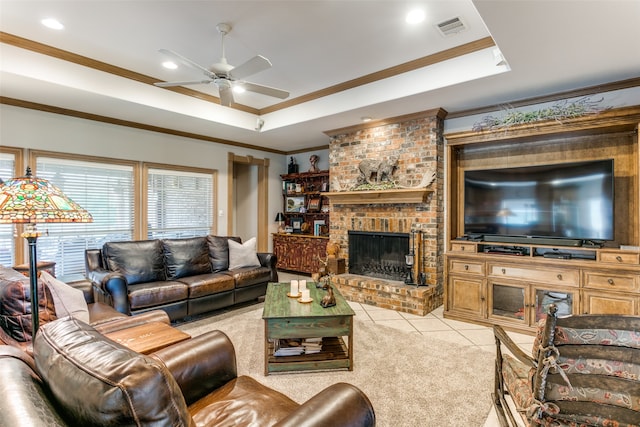 tiled living room with a brick fireplace, a raised ceiling, ornamental molding, and ceiling fan