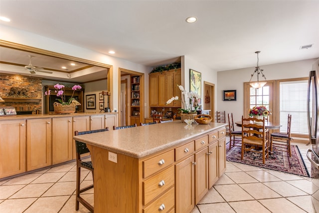 kitchen featuring hanging light fixtures, a breakfast bar, a kitchen island, light tile patterned floors, and ceiling fan