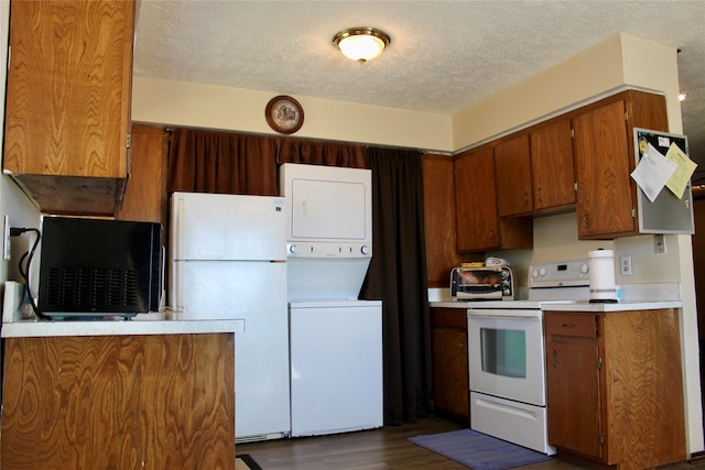 kitchen featuring a textured ceiling, stacked washer / drying machine, dark hardwood / wood-style floors, and white appliances