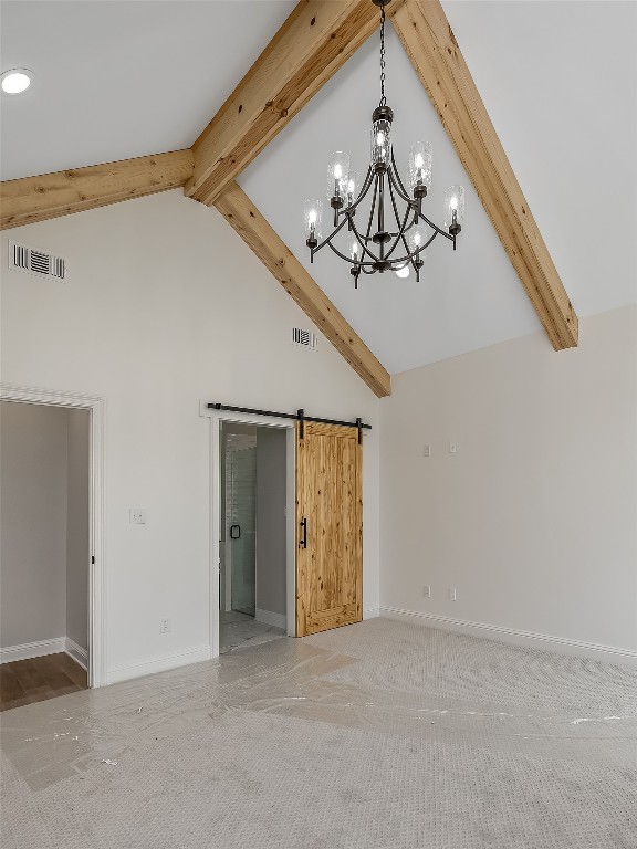 carpeted empty room featuring an inviting chandelier, high vaulted ceiling, beam ceiling, and a barn door