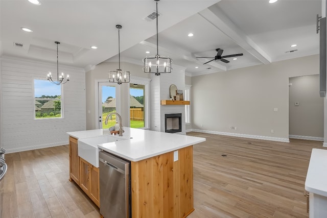 kitchen featuring light wood-type flooring, a center island with sink, dishwasher, and a fireplace