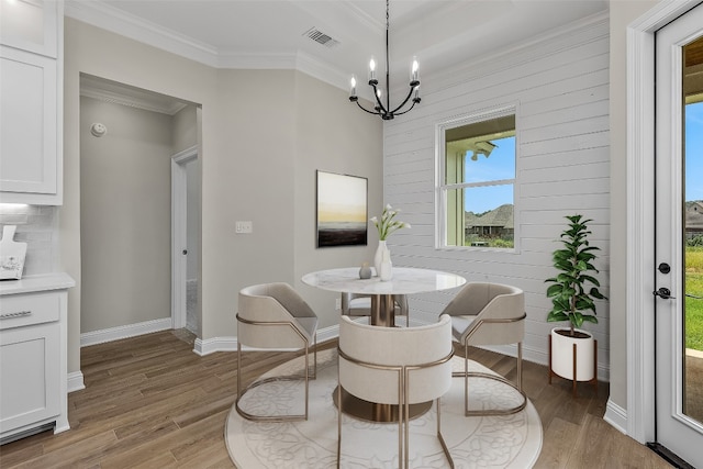 dining space featuring crown molding, a notable chandelier, and hardwood / wood-style flooring