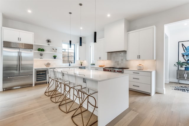 kitchen featuring a center island, built in fridge, backsplash, and white cabinetry