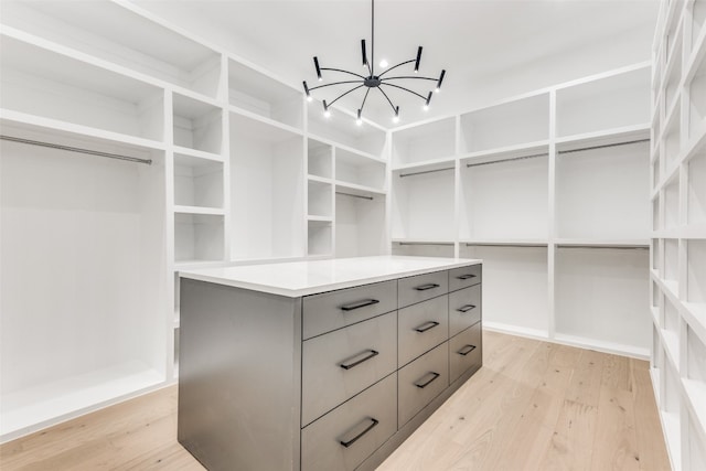 spacious closet with a chandelier and light wood-type flooring