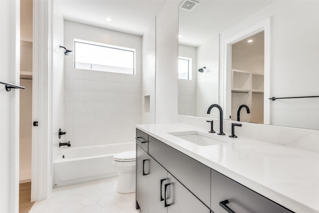 full bathroom with tiled shower / bath combo, vanity, tile floors, and toilet