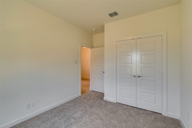 unfurnished bedroom featuring light colored carpet and a closet