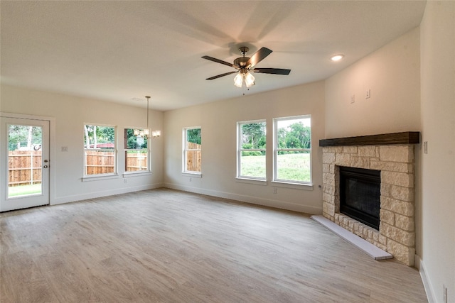 unfurnished living room with a stone fireplace, a wealth of natural light, and light hardwood / wood-style flooring