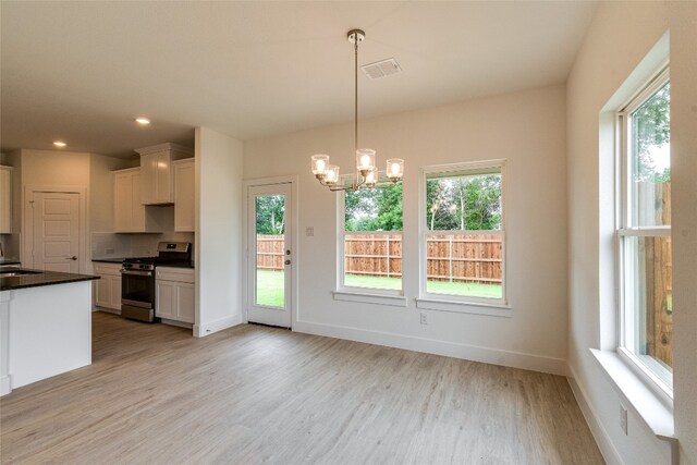 kitchen featuring a healthy amount of sunlight, gas range, light hardwood / wood-style floors, and white cabinetry