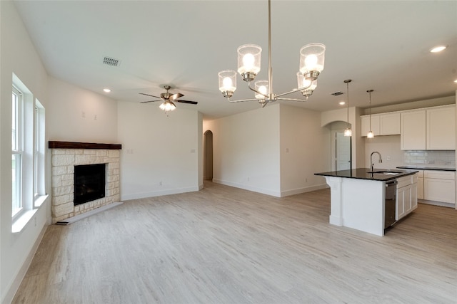 kitchen featuring backsplash, hanging light fixtures, a center island with sink, and light hardwood / wood-style flooring