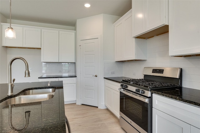 kitchen featuring white cabinets, backsplash, light hardwood / wood-style floors, decorative light fixtures, and stainless steel range with gas stovetop