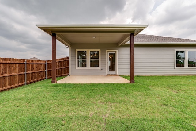 back of property with a lawn and a patio area