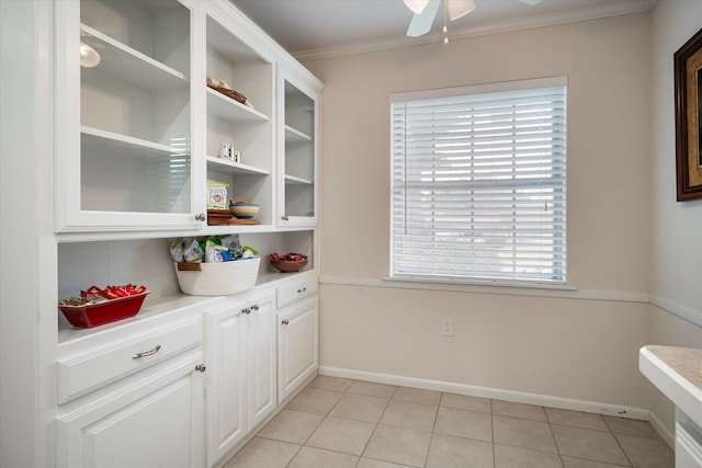 interior space with ornamental molding, ceiling fan, light tile patterned flooring, and a healthy amount of sunlight