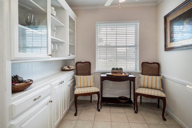 living area featuring crown molding, light tile patterned flooring, and ceiling fan