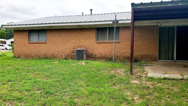 view of side of property with a yard and central AC