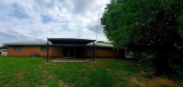 rear view of house featuring central AC unit, a lawn, and a patio area