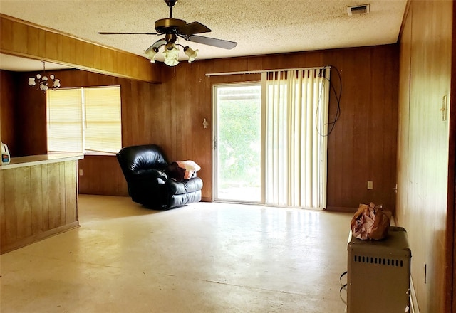 unfurnished room featuring wood walls, a textured ceiling, and ceiling fan with notable chandelier