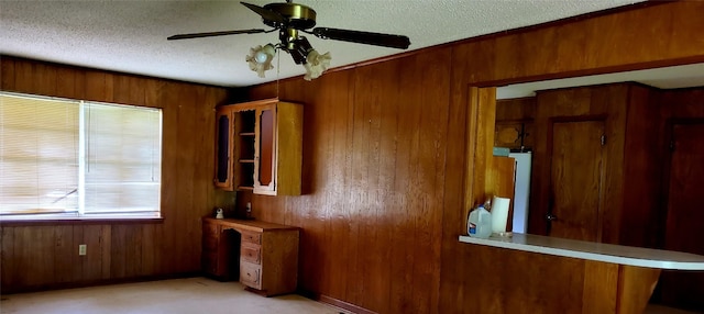 interior space with a textured ceiling, wooden walls, and ceiling fan