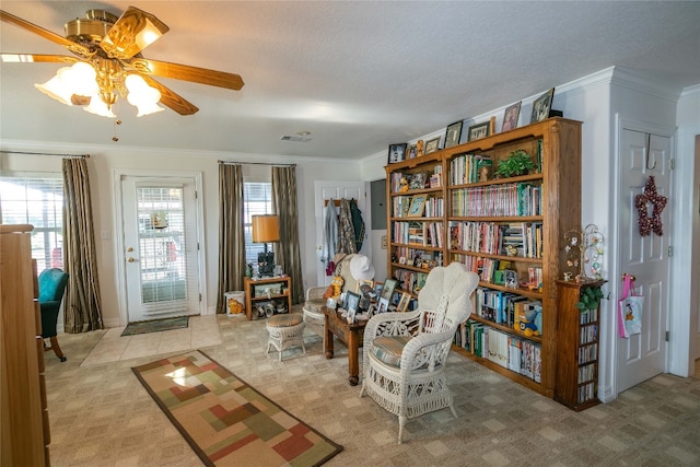 sitting room featuring ceiling fan, a textured ceiling, ornamental molding, and light carpet