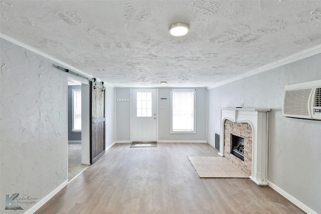 unfurnished living room with hardwood / wood-style flooring, a barn door, a textured ceiling, and a wall mounted air conditioner