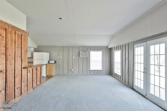 interior space featuring vaulted ceiling, light colored carpet, and a wall mounted air conditioner