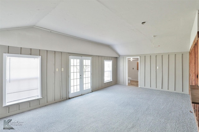 carpeted empty room featuring french doors and vaulted ceiling