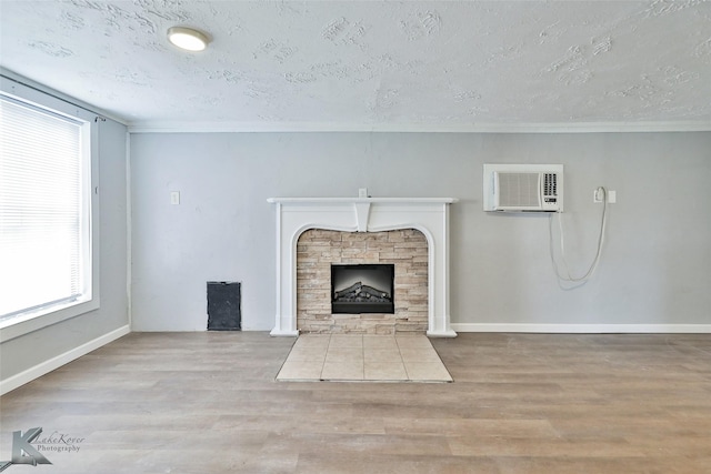 unfurnished living room featuring a stone fireplace, a textured ceiling, and light wood-type flooring