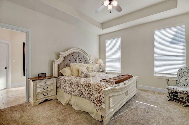 bedroom featuring a raised ceiling, ceiling fan, and light tile flooring