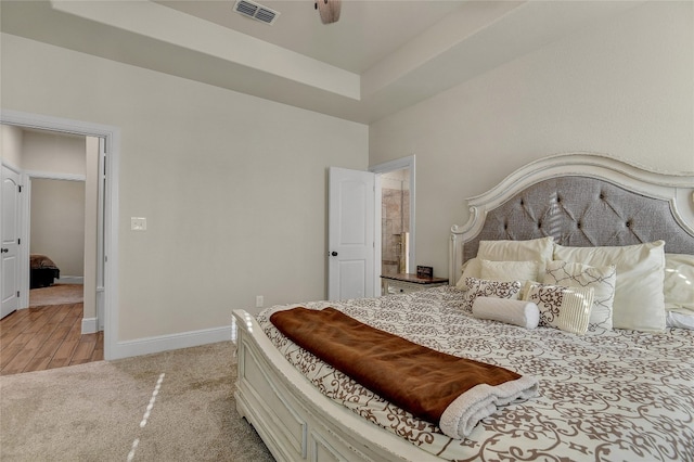 bedroom featuring a raised ceiling, light colored carpet, and ceiling fan