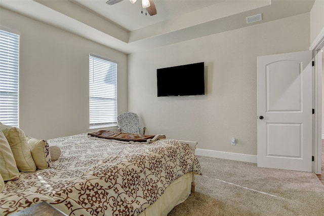 bedroom featuring ceiling fan, a raised ceiling, and light carpet