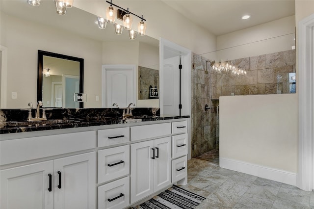 bathroom featuring double sink vanity, tile floors, a tile shower, and a chandelier