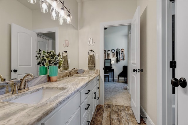 bathroom with double sink, large vanity, and wood-type flooring