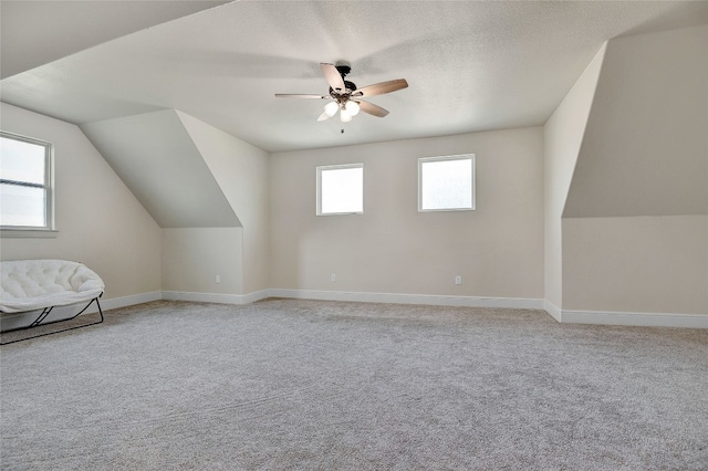 bonus room featuring lofted ceiling, light colored carpet, ceiling fan, and a textured ceiling