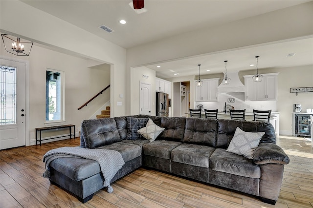 living room featuring an inviting chandelier, beverage cooler, light hardwood / wood-style floors, and sink