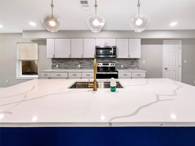 kitchen featuring white cabinets, hanging light fixtures, and stainless steel appliances