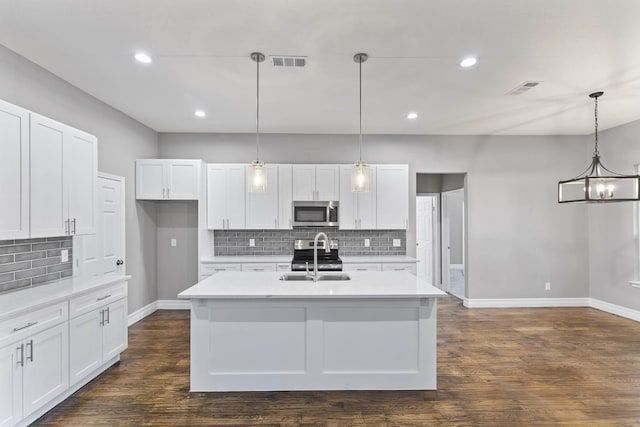 kitchen featuring white cabinets, appliances with stainless steel finishes, dark hardwood / wood-style floors, and pendant lighting