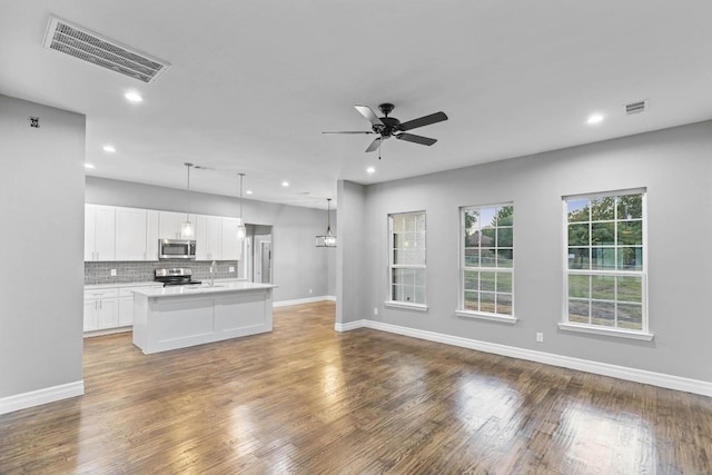 unfurnished living room featuring ceiling fan, wood-type flooring, and sink