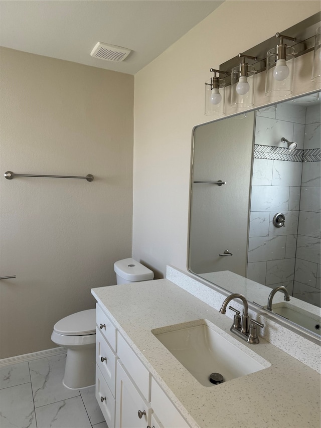 bathroom with tiled shower, vanity, and toilet