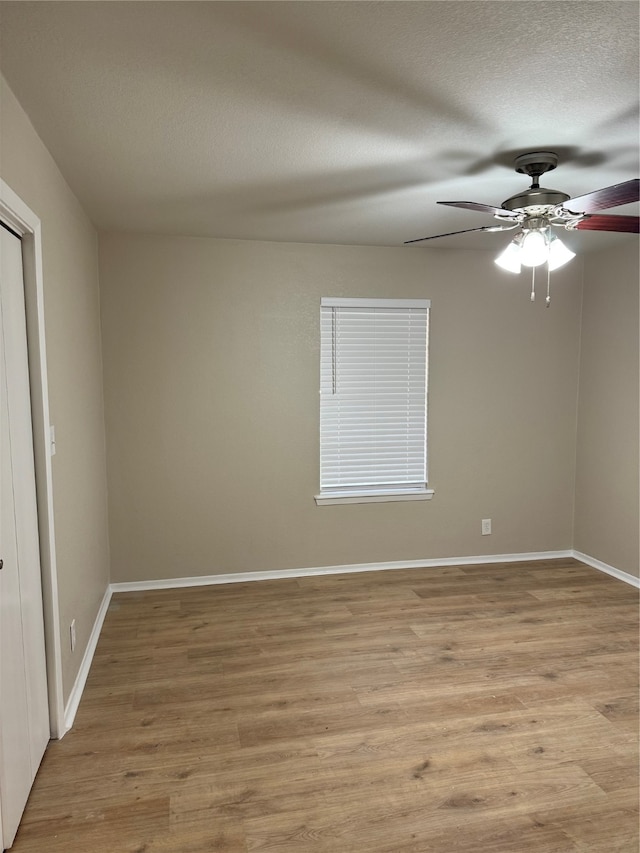 empty room featuring a textured ceiling, light wood-type flooring, and ceiling fan