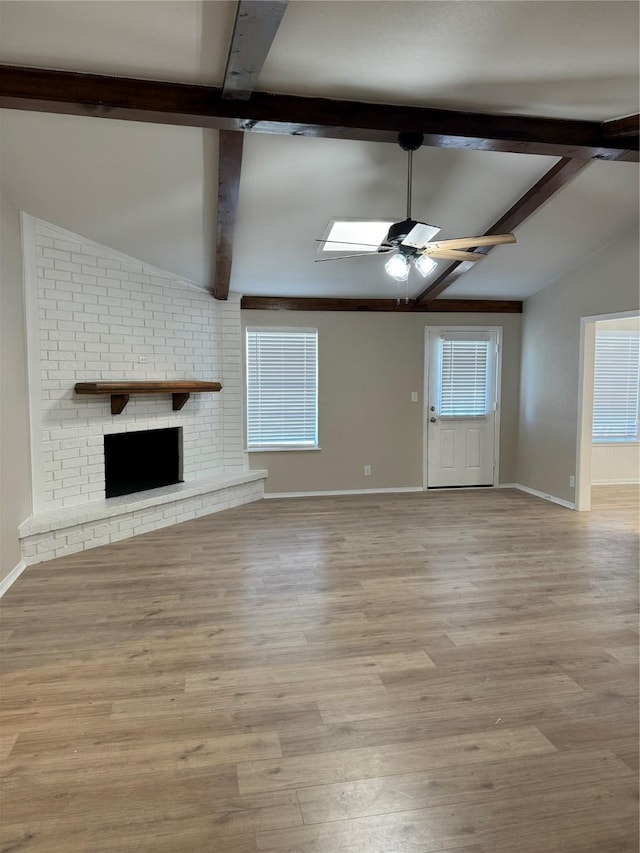 unfurnished living room with vaulted ceiling with beams, plenty of natural light, and a brick fireplace