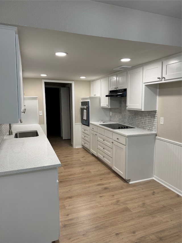 kitchen with black appliances, light hardwood / wood-style floors, white cabinets, and tasteful backsplash