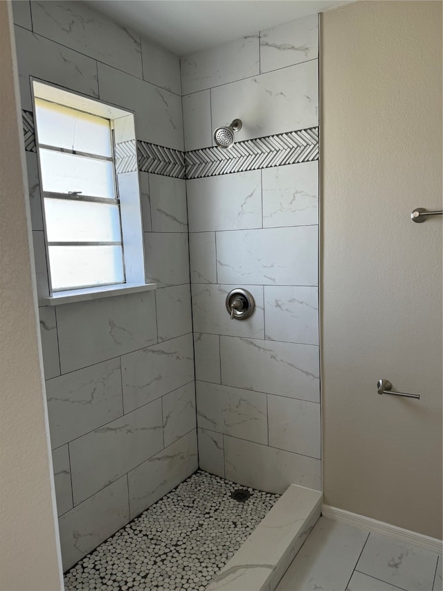 bathroom featuring a tile shower and a healthy amount of sunlight