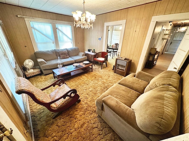 carpeted living room with a chandelier and wooden walls