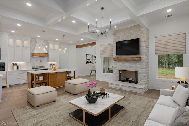 living room with a fireplace, light wood-type flooring, and beamed ceiling