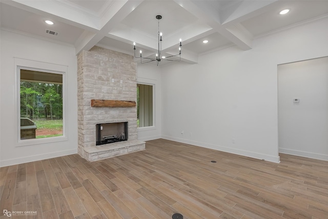 unfurnished living room with a stone fireplace, beamed ceiling, a chandelier, and coffered ceiling