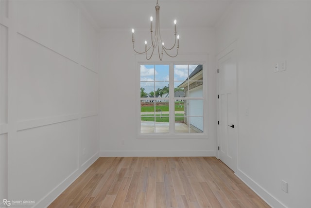 unfurnished dining area with light hardwood / wood-style floors and an inviting chandelier