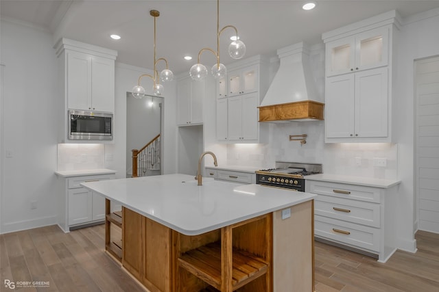 kitchen with backsplash, white cabinets, an island with sink, custom range hood, and stainless steel appliances