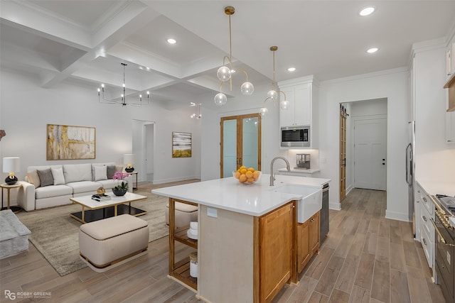 kitchen featuring a center island with sink, white cabinetry, sink, and coffered ceiling