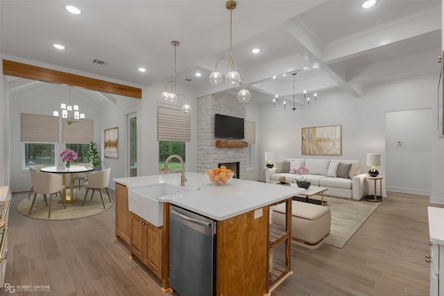 kitchen with dishwasher, a kitchen island with sink, sink, a fireplace, and beam ceiling